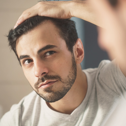 hair cta 2 man examinig his hair line in the mirror